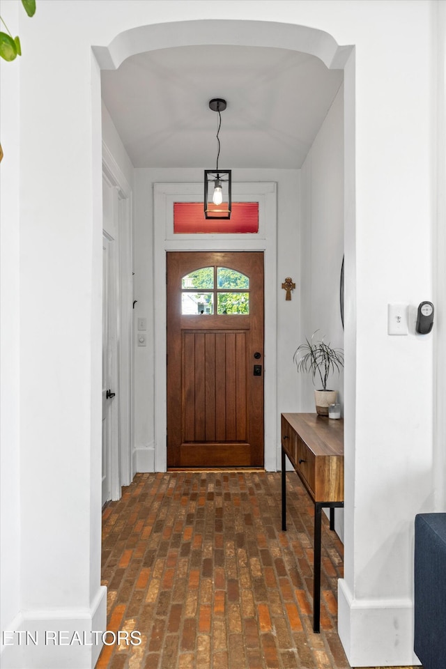 foyer with arched walkways and brick floor