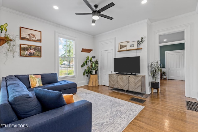 living area featuring crown molding, ceiling fan, visible vents, and wood finished floors
