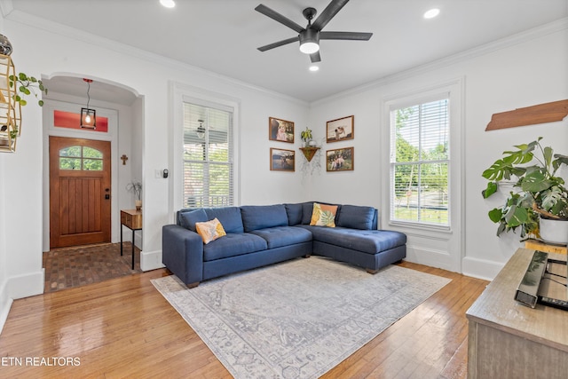 living area with plenty of natural light, arched walkways, light wood-style floors, and ceiling fan