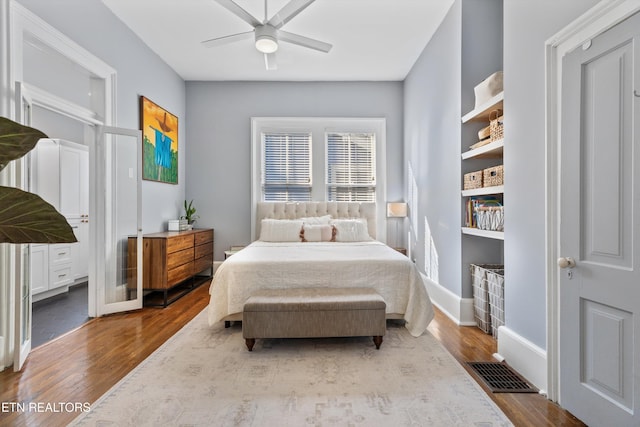 bedroom featuring visible vents, baseboards, ceiling fan, and wood finished floors