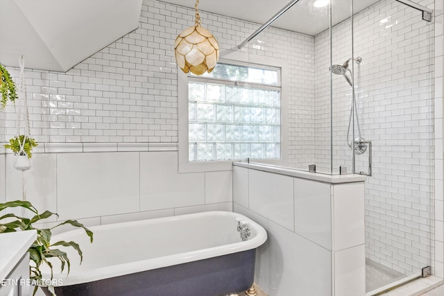 bathroom featuring a freestanding tub, tiled shower, and tile walls