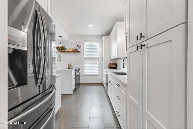 kitchen with recessed lighting, white cabinets, tasteful backsplash, a sink, and appliances with stainless steel finishes