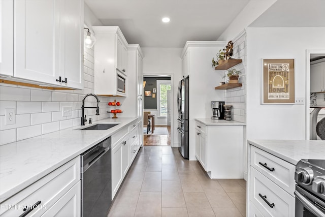 kitchen featuring white cabinets, tasteful backsplash, light stone counters, a sink, and stainless steel appliances