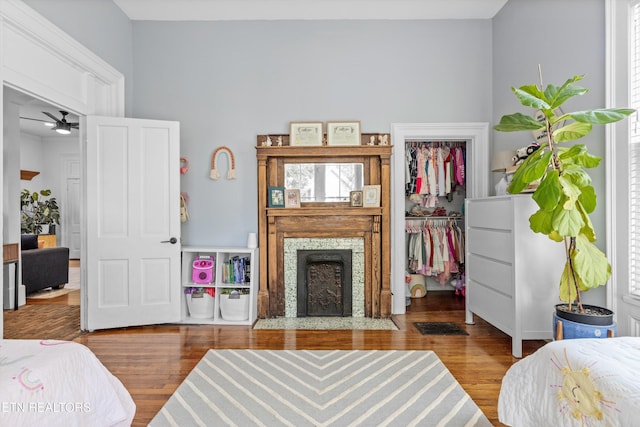 bedroom with a closet, a fireplace with flush hearth, a walk in closet, and wood finished floors