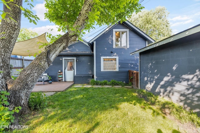 rear view of property featuring a lawn, fence, and a wooden deck