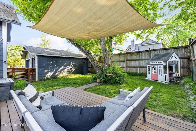 wooden terrace featuring a lawn, an outbuilding, and a fenced backyard