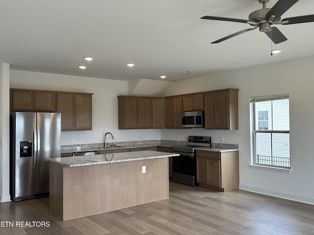 kitchen with stainless steel appliances, a kitchen island, recessed lighting, and a sink
