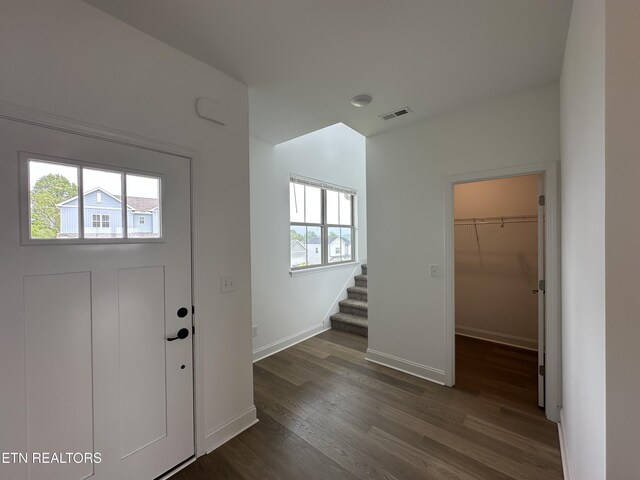 foyer entrance with dark wood-type flooring, visible vents, stairway, and baseboards