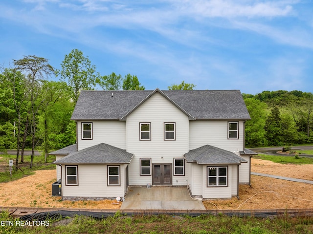 rear view of house with roof with shingles, a patio, and french doors