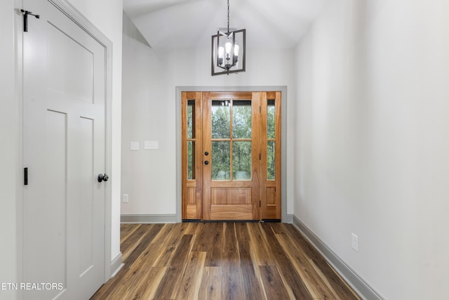 foyer entrance with baseboards, a chandelier, dark wood-type flooring, and vaulted ceiling