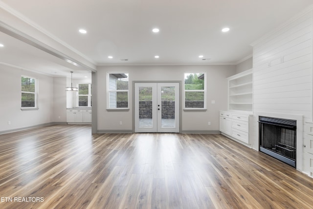 unfurnished living room featuring crown molding, a healthy amount of sunlight, and a fireplace