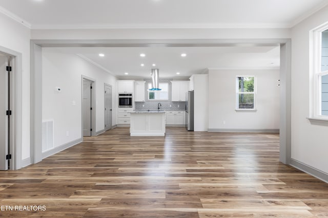 kitchen featuring appliances with stainless steel finishes, white cabinets, a center island, visible vents, and open floor plan