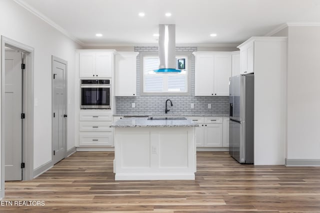 kitchen with appliances with stainless steel finishes, island range hood, white cabinetry, and crown molding