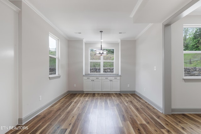 unfurnished dining area with crown molding, visible vents, hardwood / wood-style flooring, and baseboards