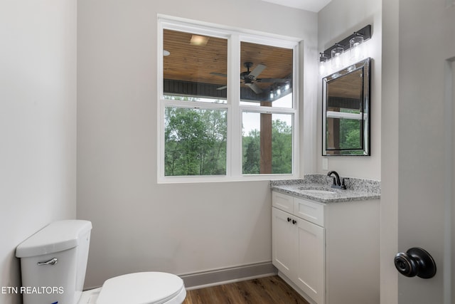 bathroom with vanity, toilet, a ceiling fan, baseboards, and wood finished floors