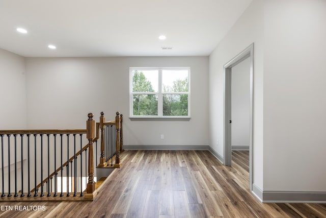 interior space with an upstairs landing, visible vents, baseboards, recessed lighting, and wood finished floors