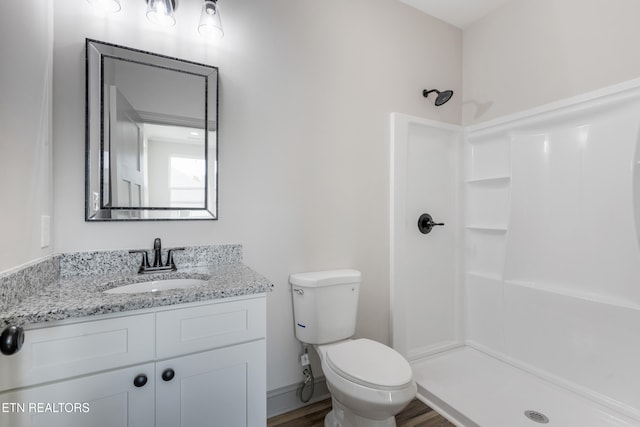 bathroom with toilet, vanity, a shower stall, and wood finished floors