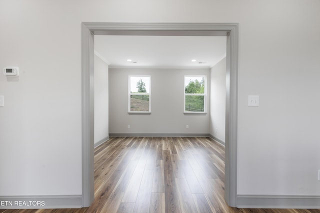 empty room with baseboards, wood finished floors, and crown molding