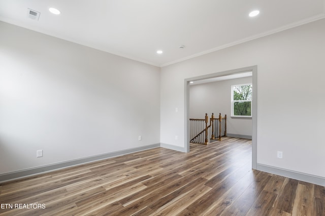 empty room featuring crown molding, visible vents, baseboards, recessed lighting, and wood finished floors