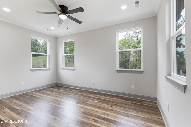 empty room with ornamental molding, visible vents, and wood finished floors