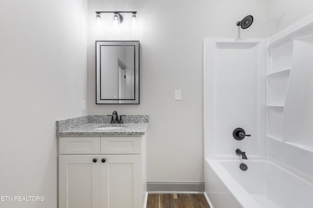 full bath with bathtub / shower combination, wood finished floors, vanity, and baseboards