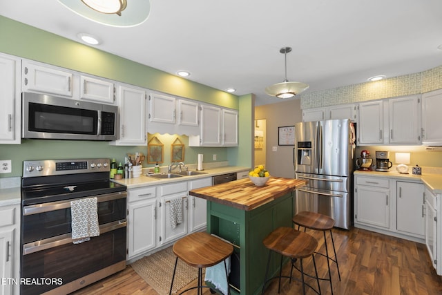 705 Kimbee Rd, Knoxville, TN 37923 - kitchen with butcher block countertops, dark wood-style floors, white cabinets, a sink, and stainless steel appliances