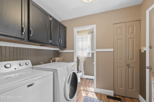705 Kimbee Rd, Knoxville, TN 37923 - clothes washing area with washing machine and clothes dryer, cabinet space, light wood-style flooring, a wainscoted wall, and visible vents