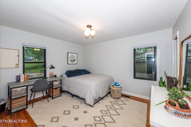 bedroom with light wood-style flooring, multiple windows, and baseboards