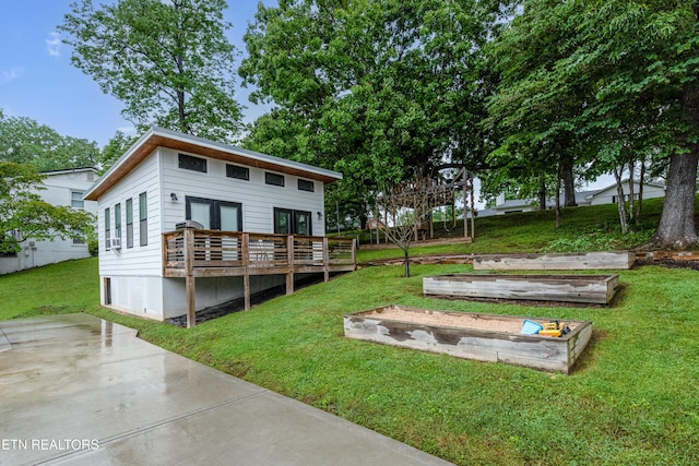 rear view of property with a garden, a yard, and a deck