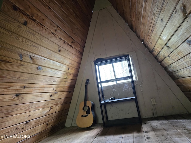 additional living space with wood-type flooring, wooden walls, vaulted ceiling, and wooden ceiling