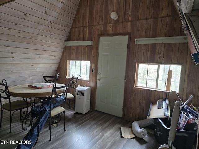 dining space with wooden walls, vaulted ceiling, and wood finished floors