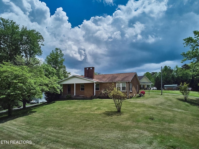 view of side of property featuring a lawn, a chimney, and brick siding