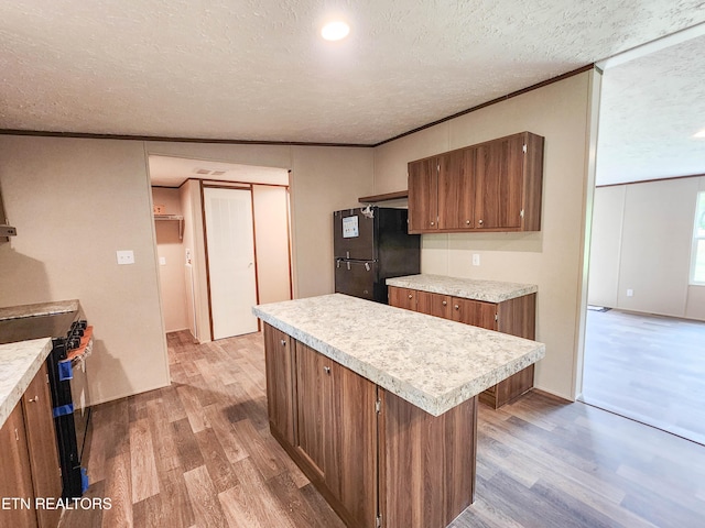 kitchen with black appliances, light countertops, light wood-style flooring, and brown cabinetry