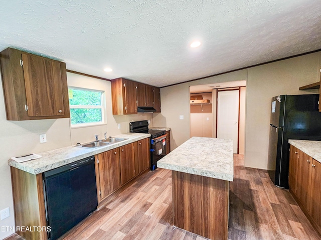 kitchen with black appliances, light countertops, light wood finished floors, and a kitchen island