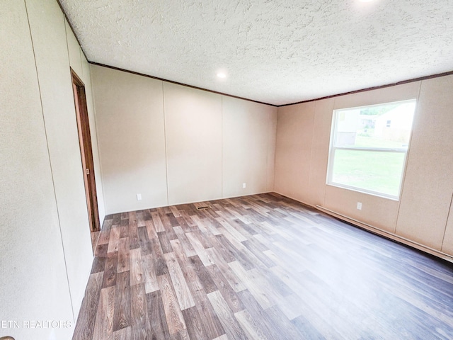 spare room with wood finished floors, a textured ceiling, and a decorative wall