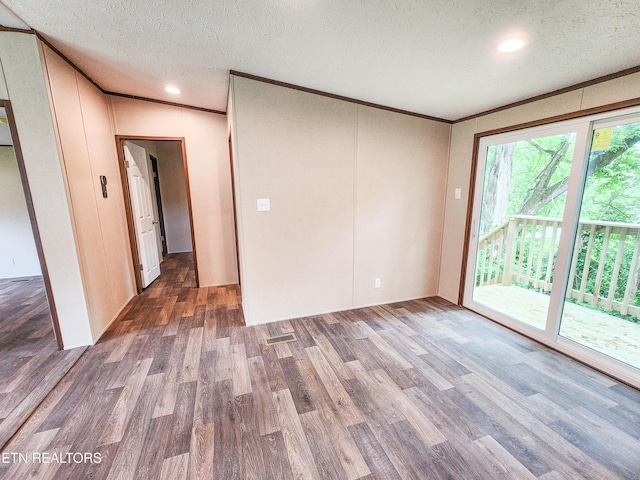 spare room featuring recessed lighting, wood finished floors, ornamental molding, visible vents, and a textured ceiling