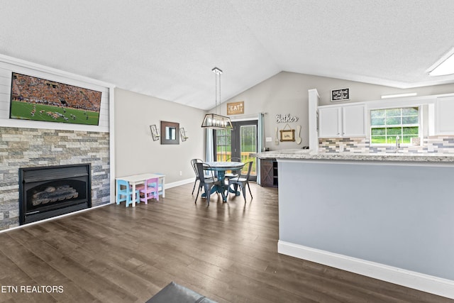 kitchen with dark wood finished floors, decorative backsplash, vaulted ceiling, white cabinets, and a textured ceiling