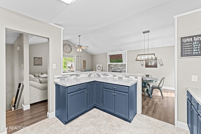 kitchen featuring hanging light fixtures, baseboards, blue cabinetry, and ceiling fan with notable chandelier