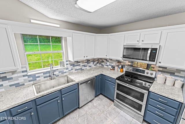 kitchen with a textured ceiling, a sink, stainless steel appliances, and blue cabinetry
