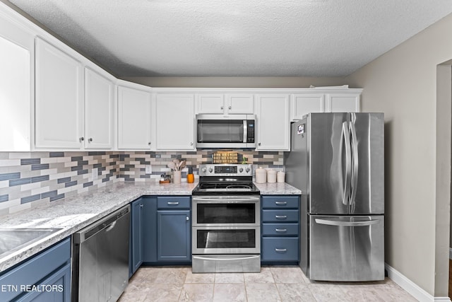 kitchen with blue cabinets, backsplash, white cabinets, and appliances with stainless steel finishes
