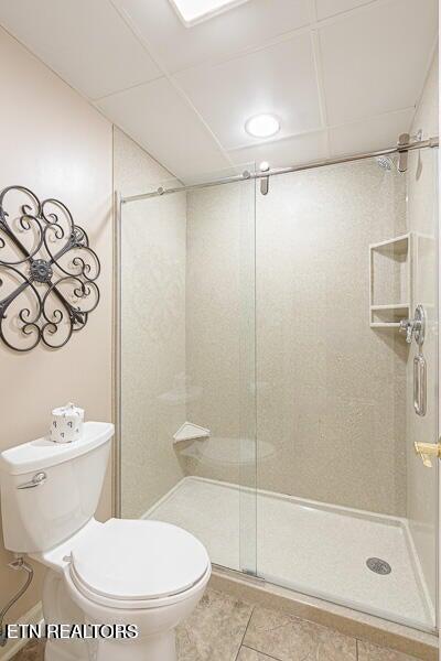 full bathroom with a shower stall, toilet, and tile patterned flooring