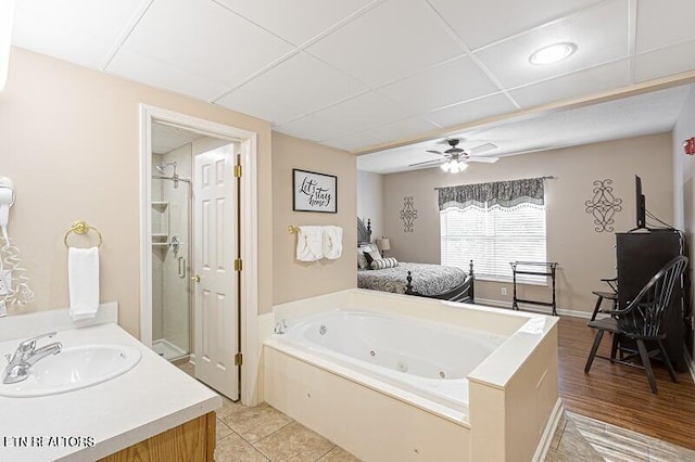 full bathroom featuring a stall shower, a ceiling fan, vanity, and a jetted tub