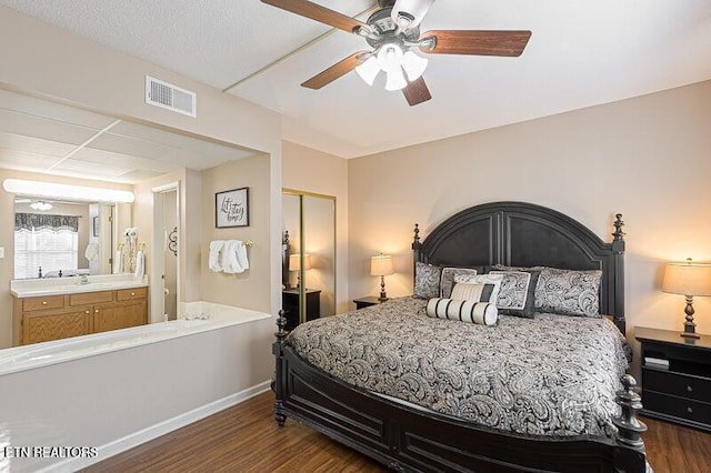 bedroom featuring a sink, a closet, visible vents, baseboards, and wood finished floors