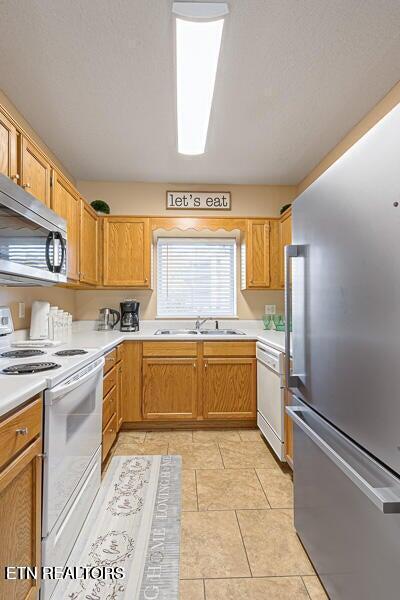 kitchen featuring light tile patterned floors, a sink, stainless steel appliances, and light countertops