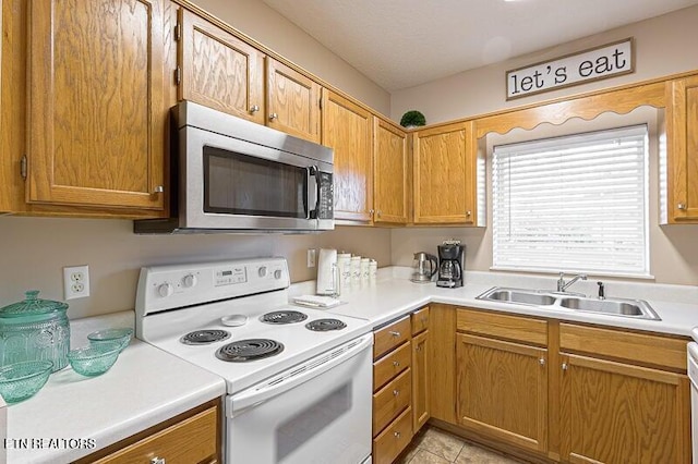 kitchen with stainless steel microwave, a sink, light countertops, white range with electric cooktop, and brown cabinetry
