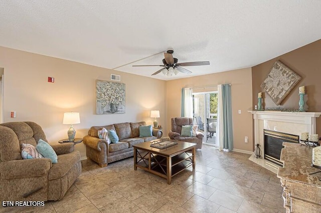 living area featuring visible vents, a tiled fireplace, a ceiling fan, and baseboards