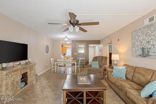 living room with a textured ceiling, visible vents, a ceiling fan, and baseboards