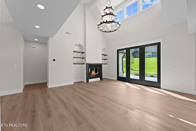 922 Eagle Point Dr, Loudon, TN 37774 - unfurnished living room featuring a towering ceiling, visible vents, a chandelier, light wood-style flooring, and baseboards