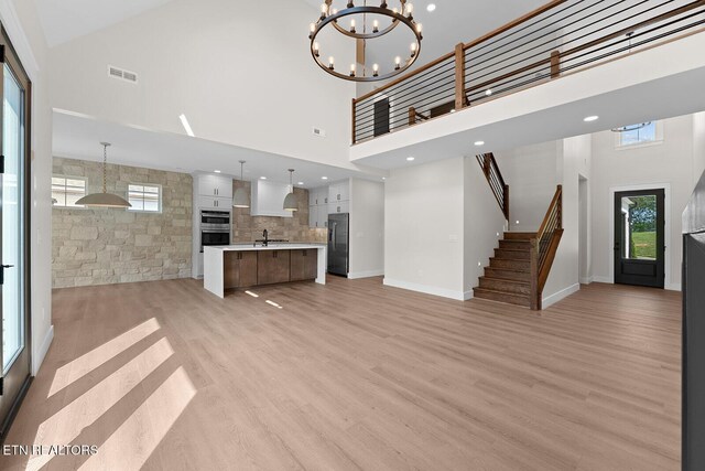 922 Eagle Point Dr, Loudon, TN 37774 - unfurnished living room with a notable chandelier, visible vents, stairs, a towering ceiling, and light wood-style floors