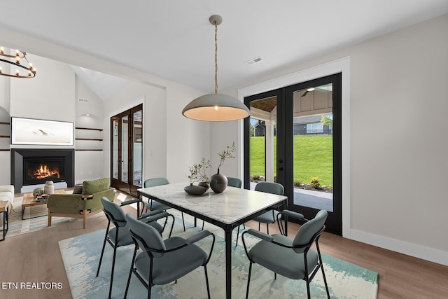 922 Eagle Point Dr, Loudon, TN 37774 - dining space featuring a warm lit fireplace, french doors, baseboards, visible vents, and wood finished floors